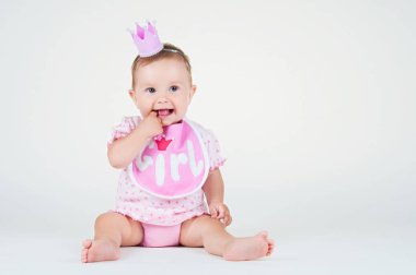 Önlük beyaz bir arka plan üzerinde oturan bir taç ile kız.