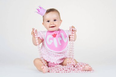 Önlük beyaz bir arka plan üzerinde oturan bir taç ile kız.