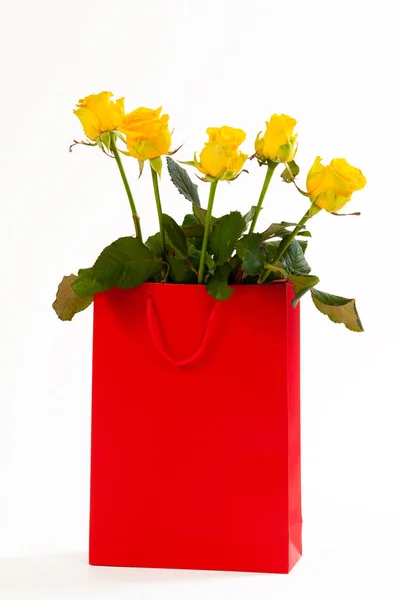 Ramo de rosas amarillas en una bolsa de papel roja, aislada sobre fondo blanco —  Fotos de Stock