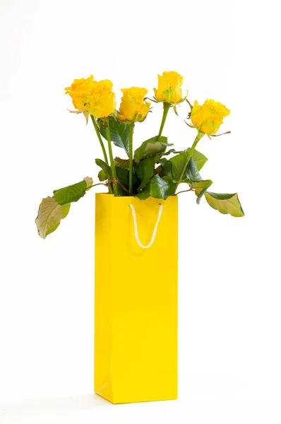 Yellow roses bouquet in a yellow paper bag, isolated on white background. — Stock Photo, Image