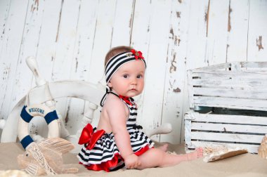 Neşeli küçük kız deniz bir tarzda kumsalda oturur