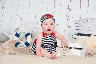 Neşeli küçük kız deniz bir tarzda kumsalda oturur