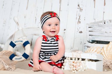 Neşeli küçük kız deniz bir tarzda kumsalda oturur