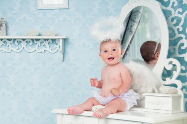 Gülümseyen ve soyunma masada oturan küçük melek