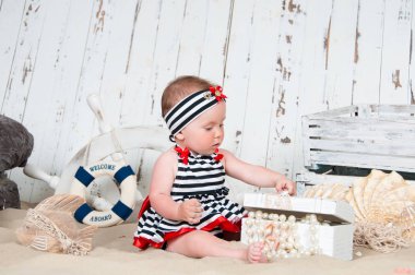 Neşeli küçük kız deniz bir tarzda kumsalda oturur