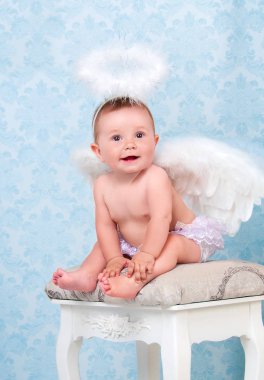 Gülümseyen ve bir sandalyede oturan küçük ve mutlu melek.