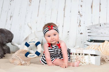 Neşeli küçük kız deniz bir tarzda kumsalda oturur