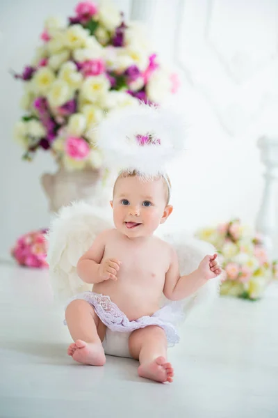 Piccolo angelo sorridente e felice seduto sullo sfondo di fiori e arpa — Foto Stock