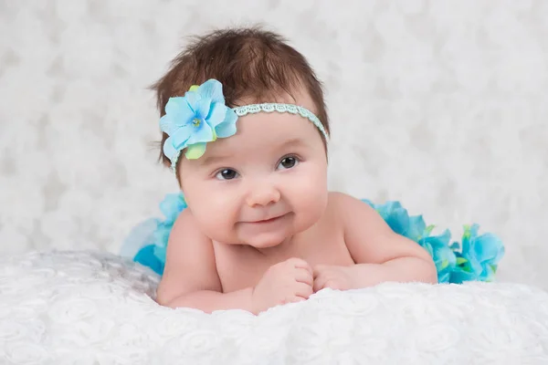 Retrato recién nacido de una niña con un vendaje tejiendo una flor azul —  Fotos de Stock