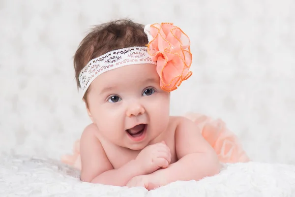 Newborn girl portrait with knitted bandage in the form of a flower. — Stock Photo, Image