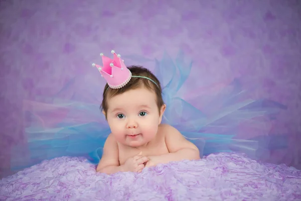 Portrait of newborn girl smiling in a pink crown — Stock Photo, Image