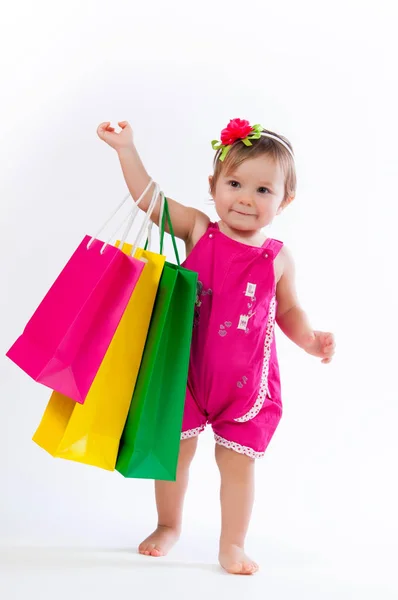 Petite fille debout avec des sacs en papier coloré isolé sur fond blanc . — Photo