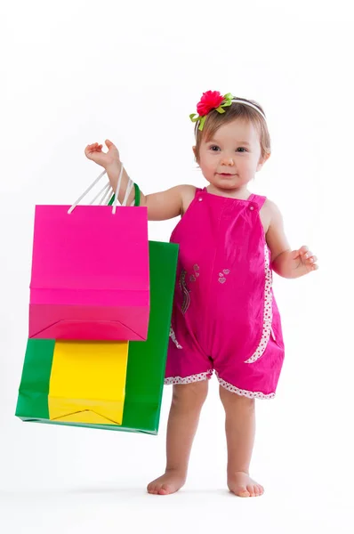 Little girl standing with colorful paper bags isolated on white background. — Stock Photo, Image