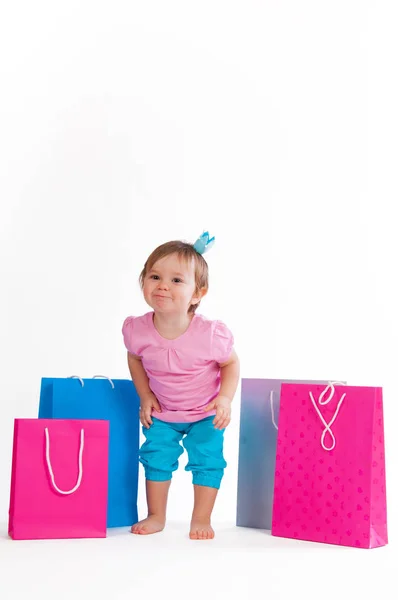Little girl hamming stands with colorful paper bags. — Stock Photo, Image
