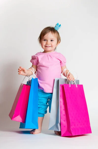 Douce fille au design rose et bleu avec des sacs en papier isolés sur fond blanc . — Photo