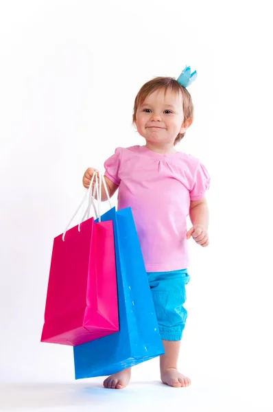 Słodka dziewczyna w projekt różowy i niebieski z torby papierowe na białym tle. — Zdjęcie stockowe