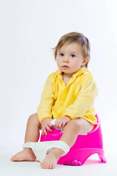 Uma menina sorridente sentada numa panela. Isolado sobre fundo branco . — Fotografia de Stock