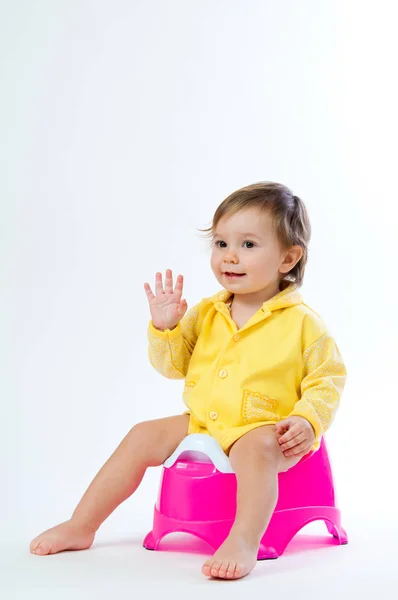 Uma menina sorridente sentada numa panela. Isolado sobre fundo branco . — Fotografia de Stock