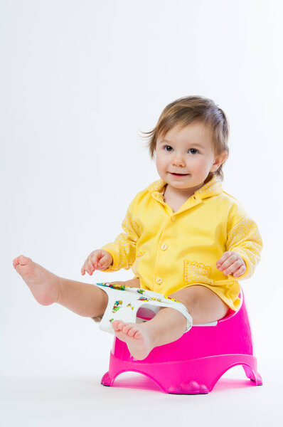 Little smiling girl sitting on a pot. Isolated on white background.