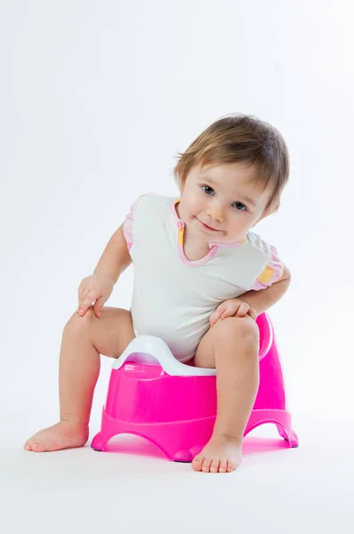 Uma menina sorridente sentada numa panela. Isolado sobre fundo branco . — Fotografia de Stock