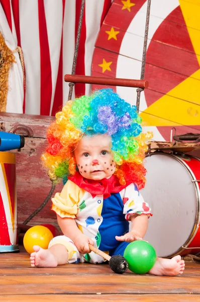 Lilla baby clown med röd näsa flerfärgad peruk in med bollar — Stockfoto