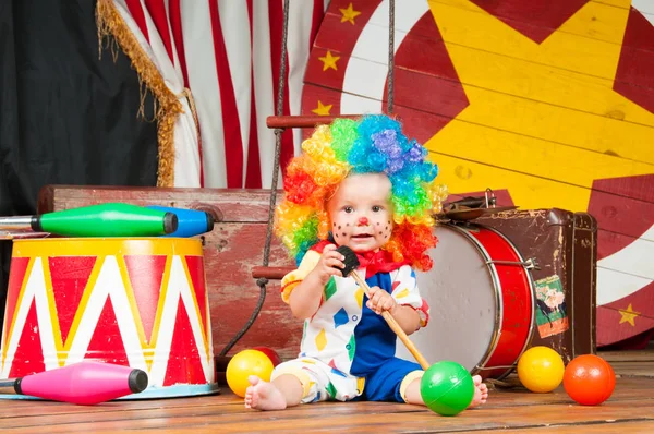 Lilla baby clown med röd näsa flerfärgad peruk in med bollar — Stockfoto