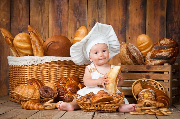 Pequeño niño cocina un croissant en el fondo de cestas con rollos y pan . —  Fotos de Stock