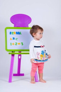 Küçük bir kız kurulu harf ve rakam ile yakın duruyor.