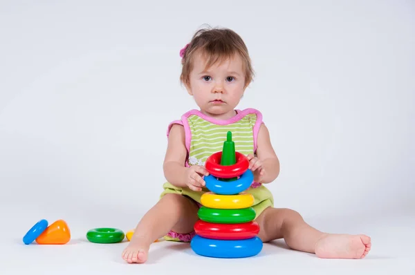 Милая маленькая девочка играет с игрушечной пирамидой — стоковое фото