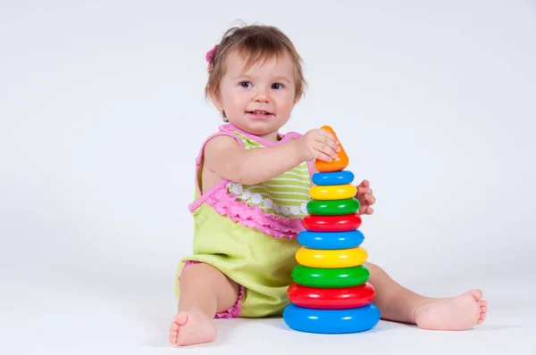 Schattig klein meisje verzamelt een speelgoed-piramide. Rechtenvrije Stockafbeeldingen