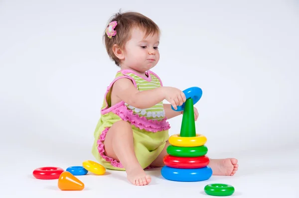 Милая маленькая девочка играет с игрушечной пирамидой — стоковое фото
