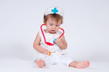 Bir doktor olarak bir stetoskop ile oynarken bir neşeli gülen kız bebek.