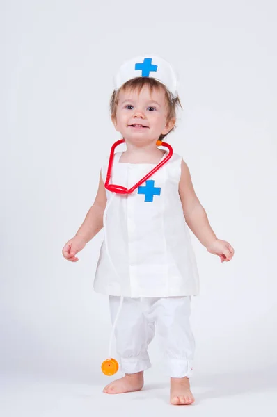 A cheerful laughing baby girl playing as a doctor with a stethoscope. Stock Image