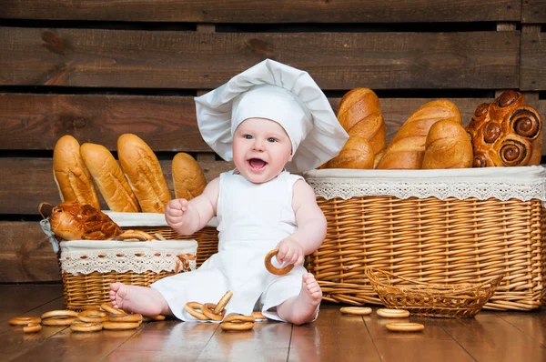 Kind kocht Croissant im Hintergrund aus Körben mit Brötchen und Brot. — Stockfoto