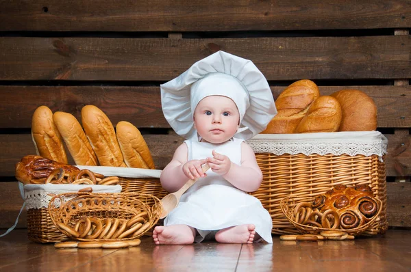 Kind kocht Croissant im Hintergrund aus Körben mit Brötchen und Brot. — Stockfoto
