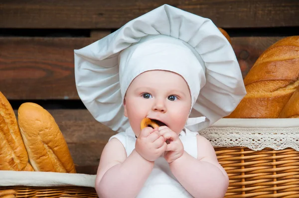Porträt Kind kocht im Hintergrund Körbe mit Brötchen und Brot. — Stockfoto