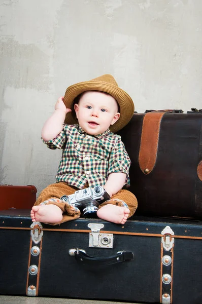 Ребенок сидит на чемодане с камерой в руках — стоковое фото