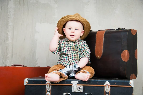 Παιδί κάθεται σε μια βαλίτσα και με μια φωτογραφική μηχανή στα χέρια του — Φωτογραφία Αρχείου