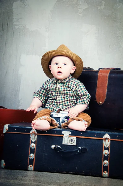 Child sits on a suitcase and with a camera in his hands — Stock Photo, Image