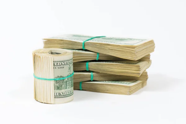 Skręconej wiązki banknotów 100-dolarowych stoi na opakowaniach dolarów. — Zdjęcie stockowe