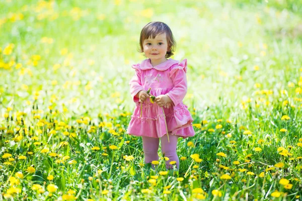 蒲公英在绿色草地上粉红色连衣裙的女孩. — 图库照片