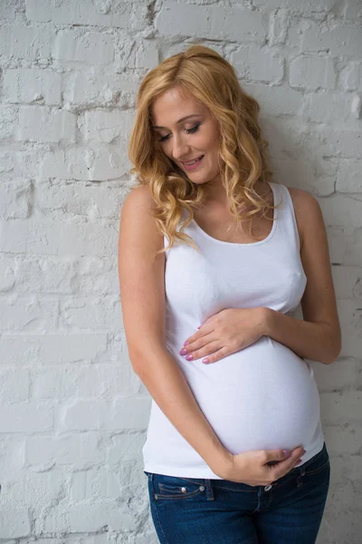 En söt gravida flicka ständiga och kramar sin mage. — Stockfoto