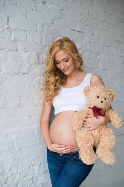 Vackra gravid flicka med en nallebjörn. — Stockfoto