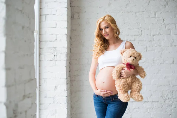 Menina grávida encantadora com um ursinho de pelúcia . — Fotografia de Stock