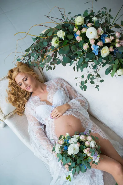 A stunningly beautiful red-haired pregnant girl with fresh flowers. — Stock Photo, Image