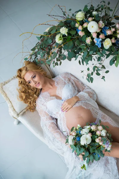 Uma linda menina grávida ruiva com flores frescas . — Fotografia de Stock