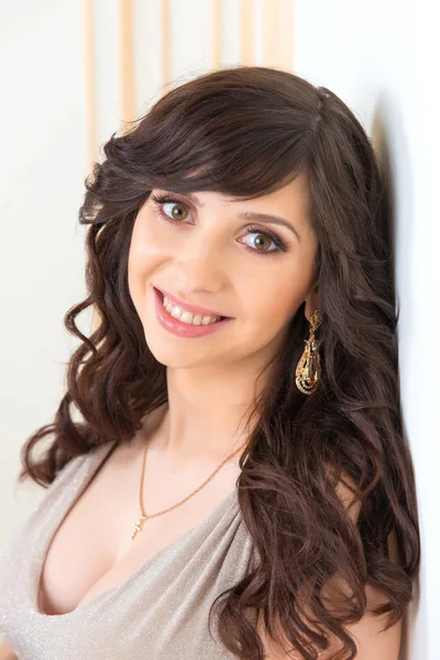 Close-up portrait of a beautiful girl in a gold dress with a neckline — Stock Photo, Image