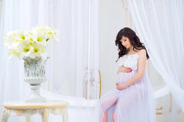 Gravidez suave. Bela grávida em vestido branco claro com orquídeas — Fotografia de Stock
