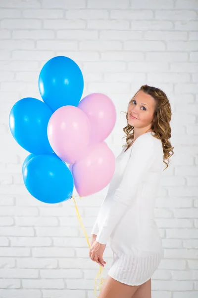 Glad gravid kvinna med ballonger i hennes hand, rosa och blå. — Stockfoto