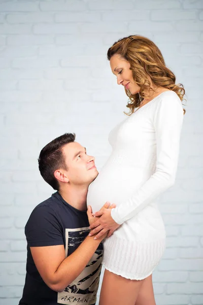 À espera do bebé. Sapatos de bebê nas mãos do pai na barriga da minha mãe . — Fotografia de Stock